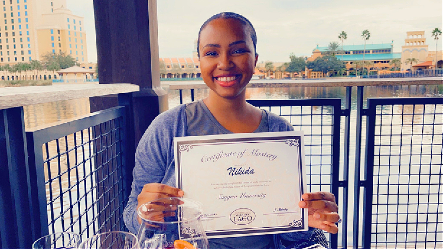 NikkyJ holding up her diploma from Sangria University at Walt Disney World