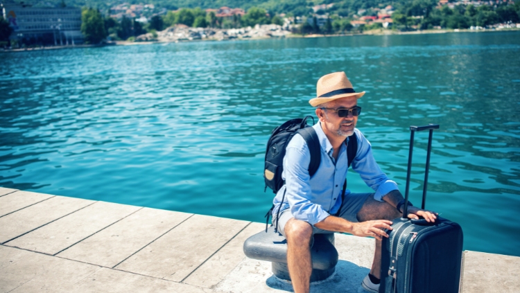 male solo traveler with luggage on dock